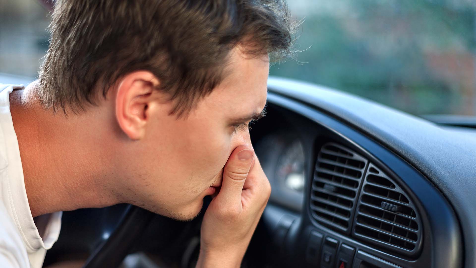 Man noticing a bad smell coming from car AC vents