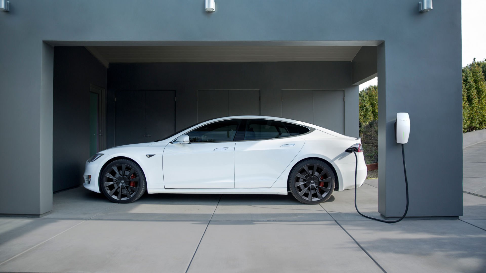 A white tesla being charged at home